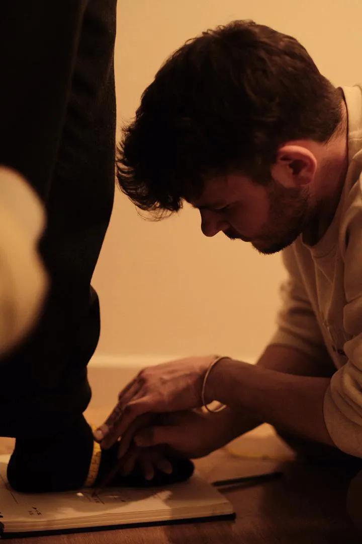 A shoemaker taking foot measurements for a pair of custom shoes